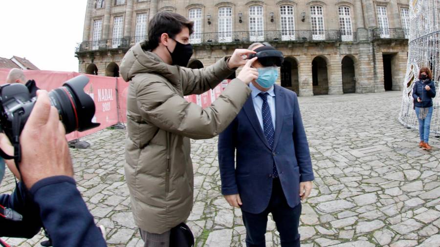 El alcalde de Santiago, Xosé Sánchez Bugallo, colocándose las gafas de realidad virtual, ayer, en el Obradoiro. Foto: F. Blanco
