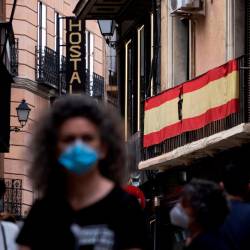 luto. Una mujer pasa ante una bandera de España con un crespón negro Foto: Efe