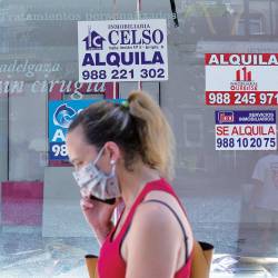 Imagen de una mujer pasando delante de un establecimiento cerrado, en la ciudad de Ourense, con varios carteles que anuncian su alquiler. Foto: Brais Lorenzo/Efe 