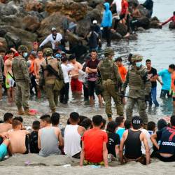 crisis migratoria. Algunas de las personas llegadas de forma irregular esta semana a Ceuta, algunos Menas, en la playa retenidos por el Ejército español. Foto: Efe