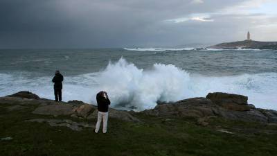 Dos personas hacen fotos de olas rompiendo contra la costa en la ciudad de A Coruña, el pasado sábado. EFE/Cabalar
