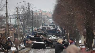 La gente mira los restos de varios vehículos militares rusos en una carretera en la ciudad de Bucha. (Fuente, www.nationalgeographic.com.es/fotografia)