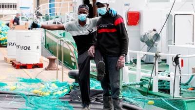Trabajadores en el puerto en el pueblo de Burela, Lugo, donde se tuvo que volver al confinamiento con apoyo judicial por un brote de coronavirus. Foto: EFE/ Eliseo Trigo