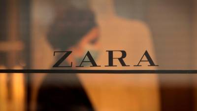 Una trabajadora reflejada en el emblemático Zara en la calle Juan Flórez de A Coruña, la primera abierta por el fundador de Inditex, Amancio Ortega. Foto: EFE/Cabalar
