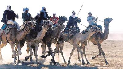 Hombres beduinos montando a camello en el Festival del Folclore beduino en Tel Arard, desierto del Neguév.