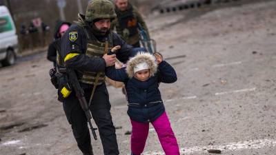 Un oficial de policía ucraniano corre sosteniendo a un niño a las afueras de Kiev mientras la artillería resuena cerca. (Fuente, www.nationalgeographic.com.es/fotografia)