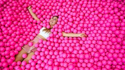 Una chica disfruta de su baño en una piscina de bolas rosas. La foto fue hecha para The Cali dreams museum en Düsseldorf, Alemania (Autor, Sascha Steinbach. Fuente, EFE)