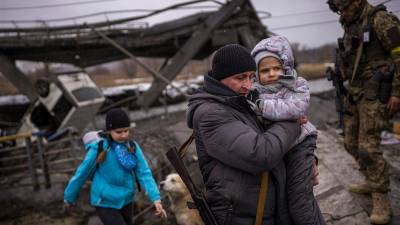 Valery, un miliciano local de 37 años, ayuda a una familia que huye a cruzar un puente destruido por la artillería en las afueras de Kiev. (Fuente, www.nationalgeographic.com.es/fotografia)