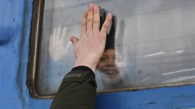 Un niño, de inocente sonrisa, se despide de un pariente a través de la ventana de un vagón de tren que espera partir desde Kramatorsk. (Fuente, www.nationalgeographic.com.es/fotografia)