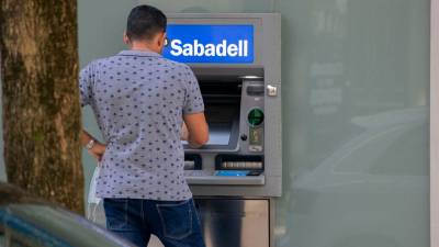 Un hombre saca dinero en el cajero de una sucursal del banco Sabadell en Santiago de Compostela. Foto: Angy A. E.