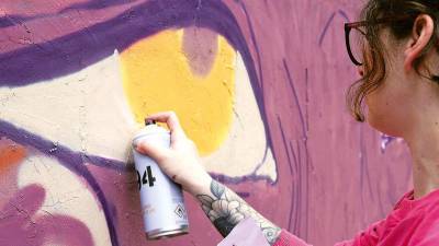 Una artista de Delas Fest durante la elaboración de un mural al aire libre. Foto: DF