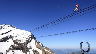 El funambulista Freddy Nock recorre 367 metros en bicicleta por el cable del teleférico en el suizo Glacier 3000 en Les Diablerets. (Autor, Laurent Gilleron. Fuente, EFE.)