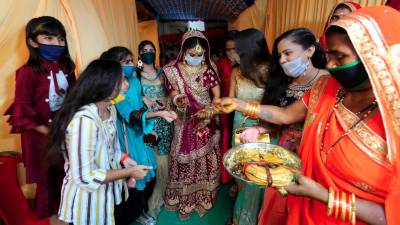 Camino a la ceremonia, Bride y sus acompañantes van cubiertas con mascarillas para evitar contagios. (Autor, Sanjeev Gupta. Fuente, EFE)