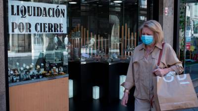 Una mujer pasa ante un comercio que anunciaba el cierre en Ourense. Foto: Efe/B. Lorenzo