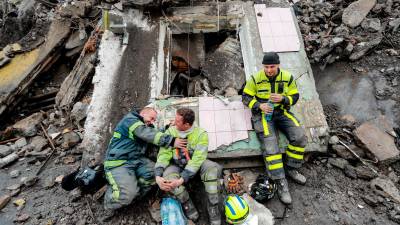 Sonrisas. Trabajadores ucranianos de búsqueda y rescate bromean durante uno de sus descansos sobre los restos de un edificio residencial que fue dañado por un bombardeo aéreo ruso . Foto: Daniel Ceng Shou 