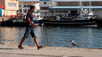 Un traballador camiña polo porto de Burela (A Mariña) durante o pico do brote na zona. Foto: EFE/Eliseo Trigo