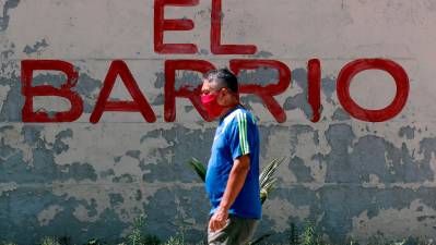 Un hombre con mascarilla pasa frente a un grafiti, en La Habana. Ernesto Mastrascusa 
