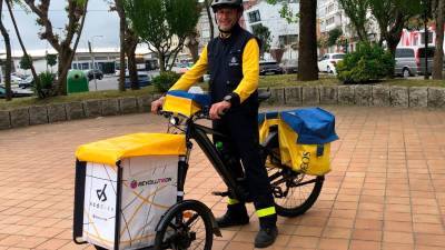 José María Boo Reiriz, sobre la bicicleta eléctrica adaptada en la que hace a diario el reparto de correo postal y paquetería en Ribeira.