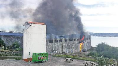 RIESGO. Los bomberos tardaron este jueves casi dos horas en extinguir el incendio declarado en el interior de la antigua fábrica de harinas de pescado Hadasa, que está ubicada al lado de un parque público en la zona de A Ribeiriña. Foto: Bomberos de Ribeira