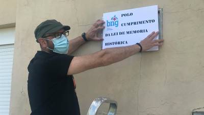 Xaime Trillo, responsable local do BNG de Dumbría, tapando a placa na antiga escola de Bustelo. Foto: BNG