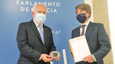 A la izquierda, el presidente del Parlamento, Miguel Ángel Santalices, tras recibir el Proxecto de Orzamentos de Galicia para 2022 de manos del conselleiro de Facenda e Administración Pública, Miguel Corgos.