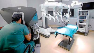 El doctor Fernando Santos en la consola del robot Da Vinci, desde donde se realiza la intervención quirúrgica, mientras otro especialista controla los brazos del instrumento. FOTO: Fernando Blanco