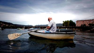 DE PESCA. Un hombre sale a pescar ayer en su bote auxiliar, fondeado en el puerto de Pontedeume. Foto: EFE / Cabalar