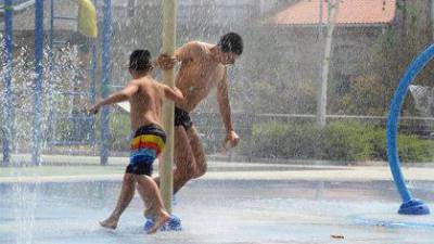 Dos personas se refrescan con chorros de la ola de calor. Foto: Rosa Veiga / E.P.