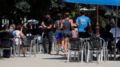 LUGO. Varios corredores pasan entre las mesas de la terraza de un bar mientras practica deporte en el Parque de Rosalía de Castro en Lugo, este martes. EFE/Eliseo Trigo