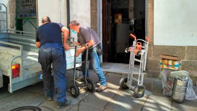 Dos personas retirando mobiliario del interior del café Derby, en As Orfas. Foto: Onda Cero