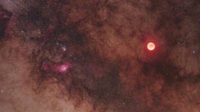 La cara roja de una Luna eclipsada brilla en la banda estelar de la Vía Láctea. (Fuente, nationalgeographic.es. Autor, Babak Tafreshi)