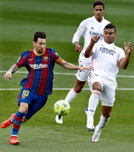 GRAF7129. BARCELONA, 24/10/2020.- El argentino Leo Messi (i), del FC Barcelona, intenta controlar el balón ante la presencia del brasileño Casemiro (d), del Real Madrid, durante el partido de la Liga de fútbol jugado esta tarde en el Nou Camp entre ambos equipos. EFE/Andreu Dalmau