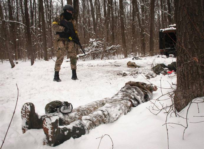 Un voluntario de las Fuerzas de Defensa Territorial de Ucrania mira el cadáver de un soldado en un bosque en las afueras de Kharkiv. (Fuente, www.nationalgeographic.com.es/fotografia)