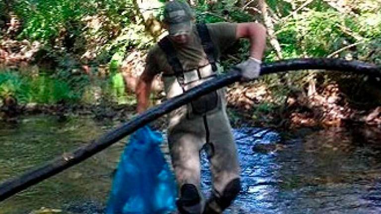 Un voluntario de Troiteiros limpiando el río