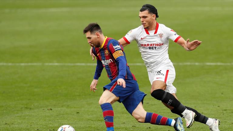 SÁNCHEZ PIZJUÁN El barcelonista Messi se escapa con el balón del jugador del Sevilla Karim Reikik. Foto: José Manuel Vidal
