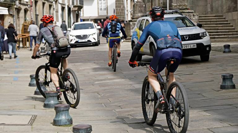 Tres ciclistas circulan por la Praza de Mazarelos de Compostela. Foto: Fernando Blanco