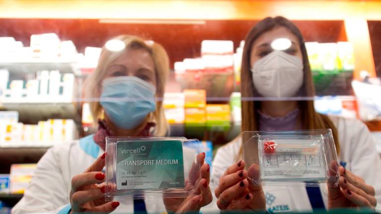 Dos farmacéuticas de Vigo con los ‘kits’ de saliva. Foto: Salvador Sas / Efe
