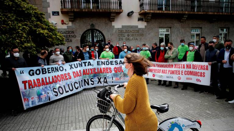 Una mujer en bicicleta pasa ante la protesta de trabajadores de la central de As Pontes y las auxiliares. Foto: Efe