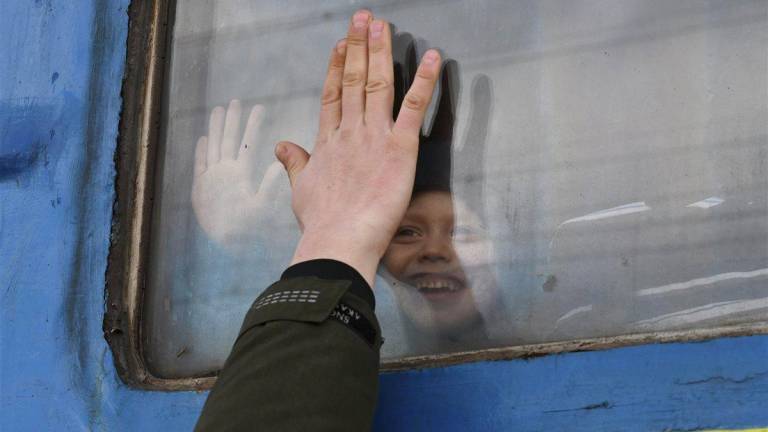 Un niño, de inocente sonrisa, se despide de un pariente a través de la ventana de un vagón de tren que espera partir desde <a rel="nofollow" href="https://es.wikipedia.org/wiki/Kramatorsk" target="_blank">Kramatorsk</a>. (Fuente, www.nationalgeographic.com.es/fotografia)
