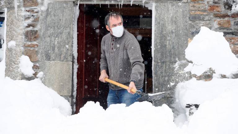 Un hombre retira la nieve que bloquea la puerta de su casa. (Autor, Eliseo Trigo. Fuente, EFE)