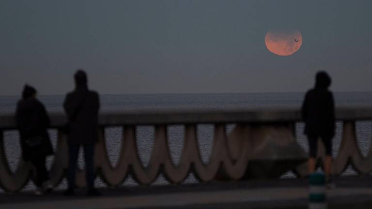 Tres personas observan el eclipse parcial de Luna desde el paseo de Riazor, en A Coruña. Foto: M. Dylan/Europa Press