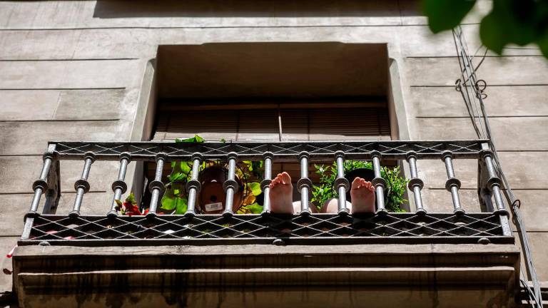 Una persona toma el sol en su balcón durante el confinamiento en Barcelona. Foto: David Zorrakino /E.Press
