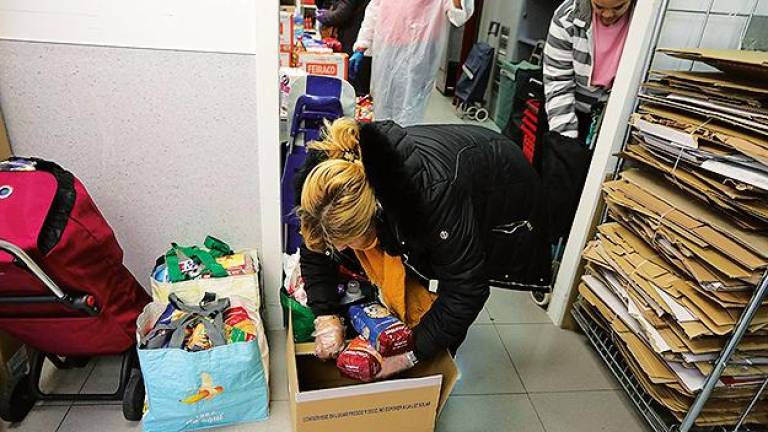 Una mujer coloca en una caja los productos que se le donan en Cáritas Madrid. Foto: E.P.