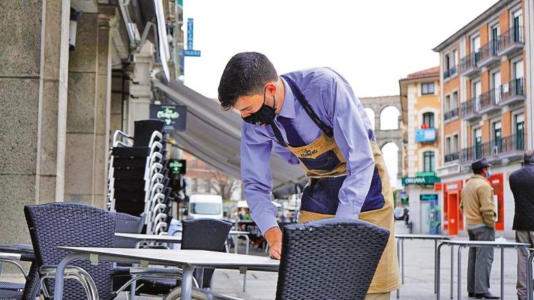 Un camarero limpia una mesa siguiendo el protocolo sanitario por la pandemia. Foto: E.P.