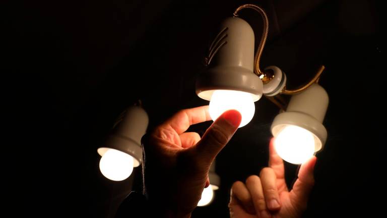 Una persona cambia la bombilla de una lámpara, el día en que el precio de la luz bate un récord histórico alcanzando los 124,45 euros por megavatio hora, a 30 de agosto de 2021, en Madrid, (España). Supone una subida de dos euros respecto al máximo. Foto: Marta Fernández / E.P.