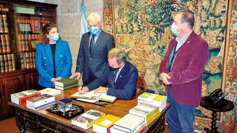 O delegado do Goberno, José Miñones, firma no libro de honra en presenza da subdelegada, María Rivas; Víctor Freixanes e Henrique Monteagudo. Foto: ECG