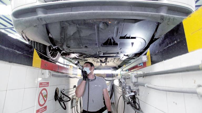 Un operario revisa los bajos de un coche en una de las estaciones de ITV de Applus+. Foto: Efe