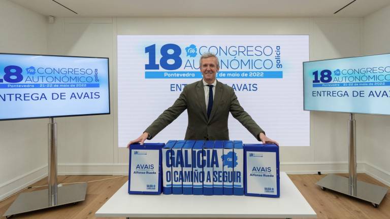 Alfonso Rueda posa junto a los tomos con los avales y el lema de su campaña para presidir el PPdeG: Galicia, o Camiño a seguir