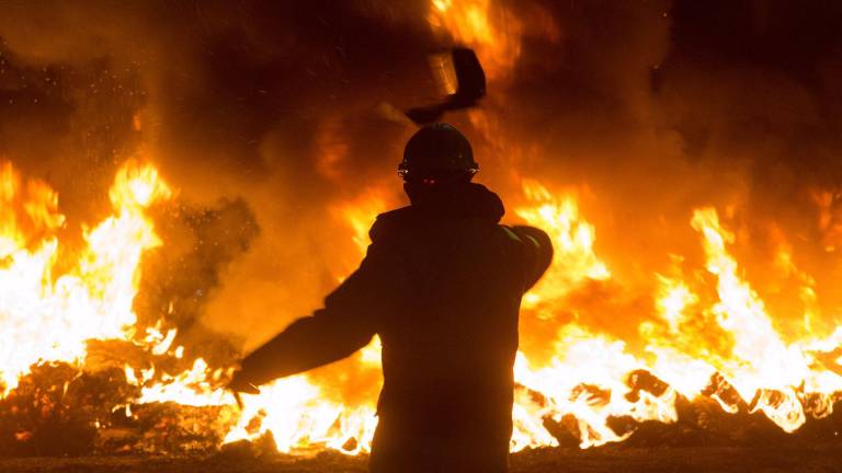 En la foto de archivo, un trabajador tira un elemento a una barricada durante un velatorio nocturno simbólico convocado por la fábrica de Alcoa. CARLOS CASTRO/EUROPA PRESS