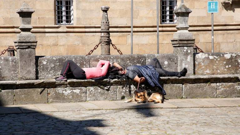 PRIMAVERA. Dos personas con su perro, ayer en la praza do Obradoiro tomando el sol y descansando. Foto: Antonio Hernández